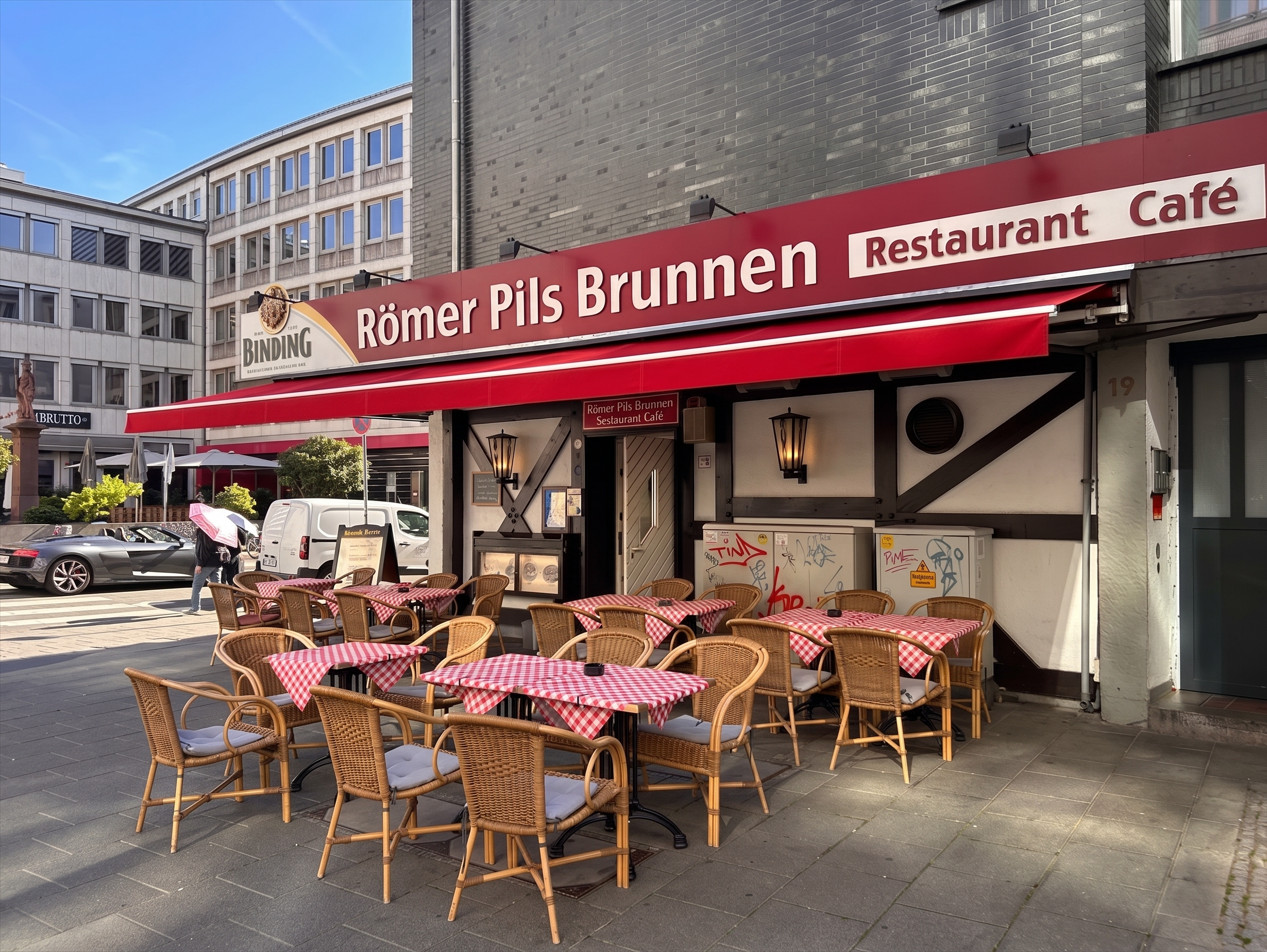 Römer Pils Brunnen restaurant exterior with red awning and outdoor tables