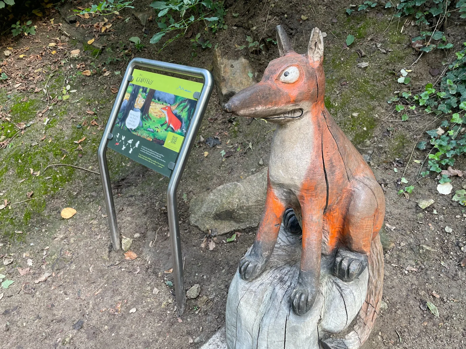 Wooden fox sculpture beside a story panel on the Grüffelo trail